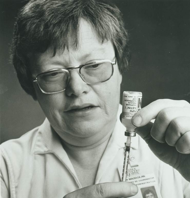 Ann Maddox in nurses uniform with syringe and vial.