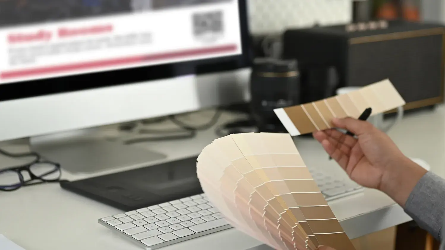 Close up of hands interacting with pantone color samples in front of their computer.