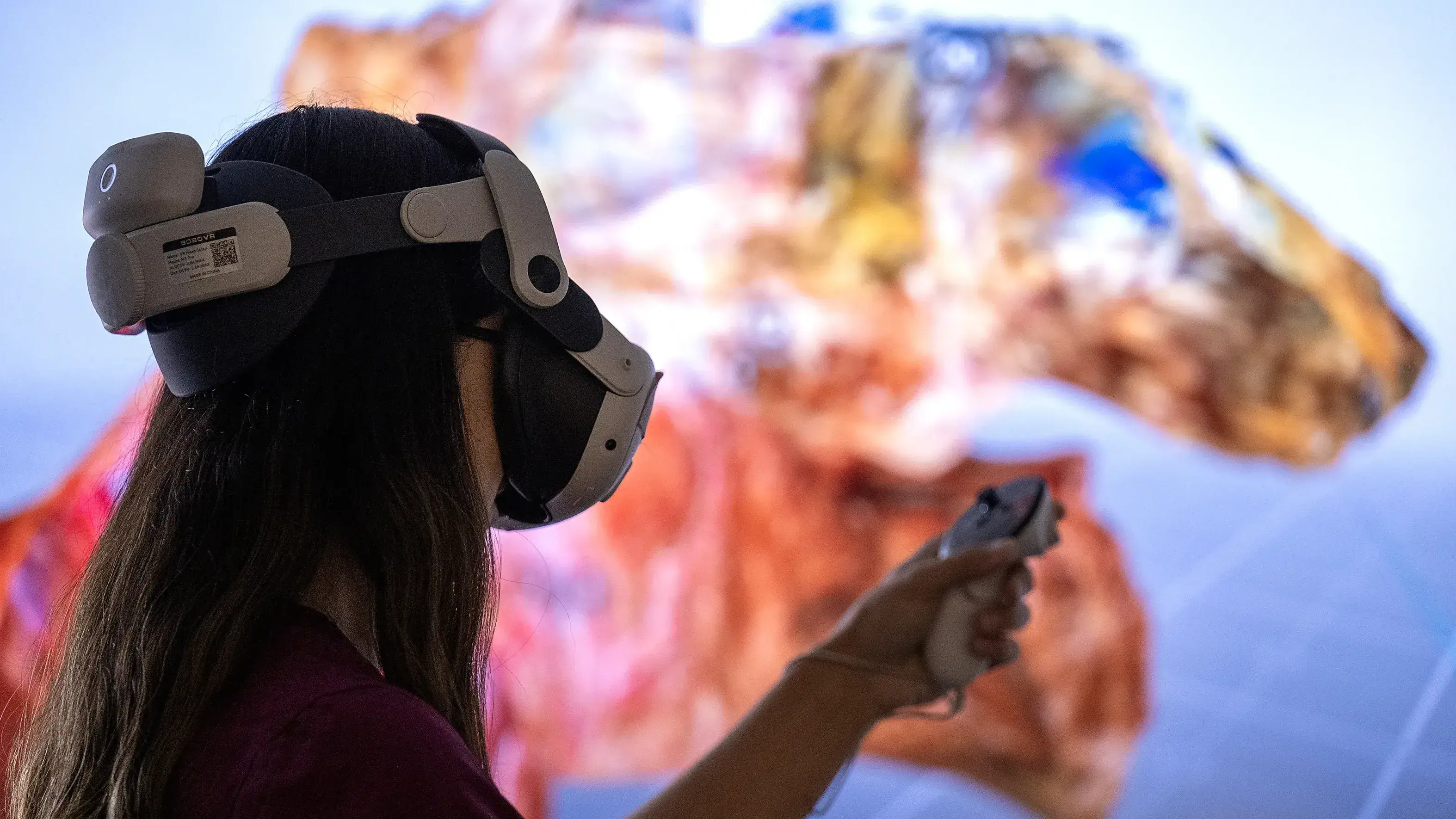 A silhouette of a woman wearing a VR headset with a brightly colored image on-screen in the background