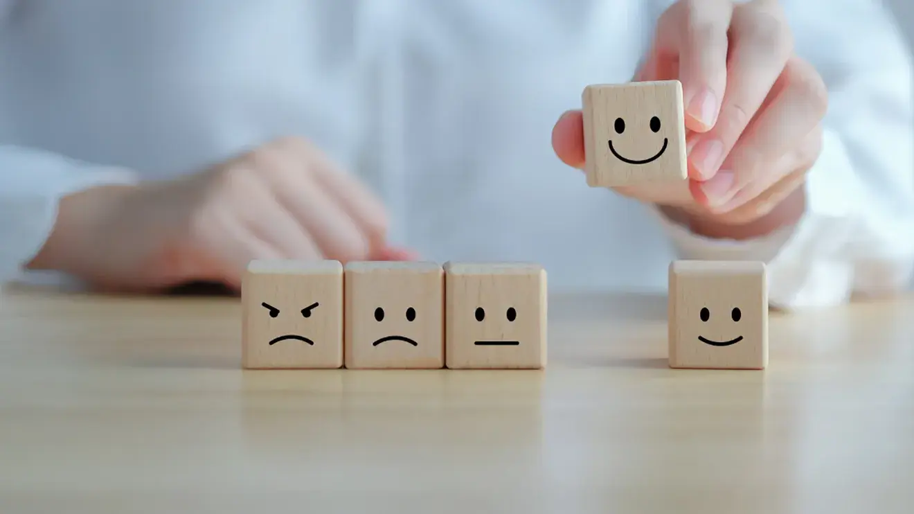 a person arranging wooden blocks with emoji faces into order