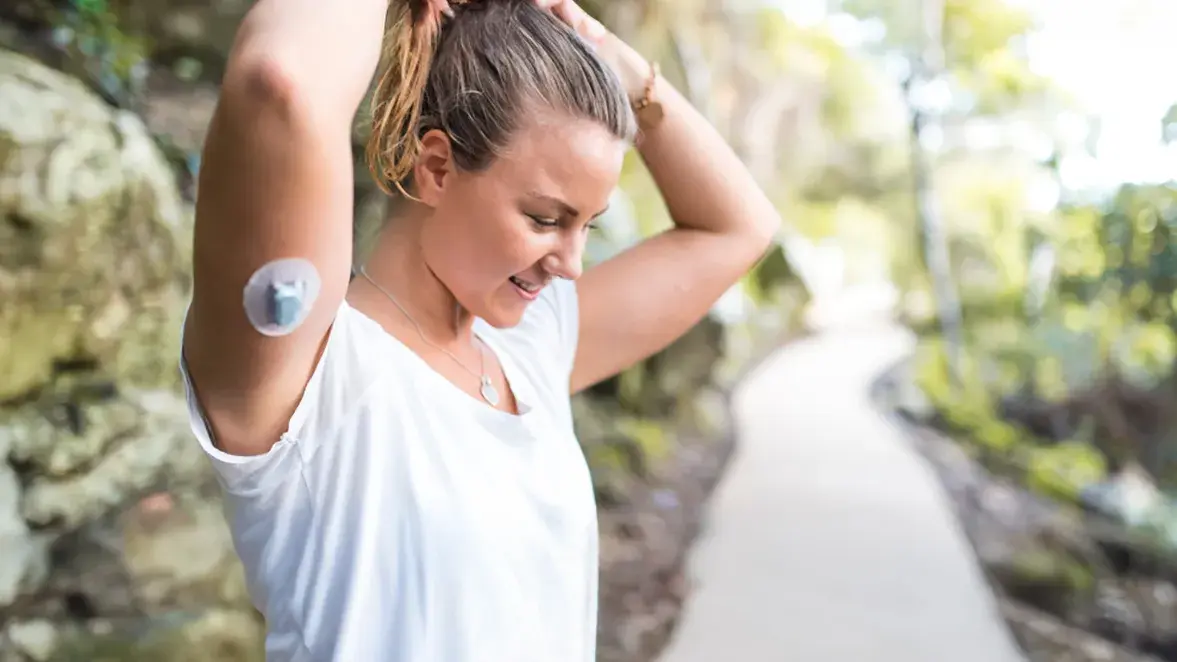 woman ties her hair into a ponytail while exercising on a trail