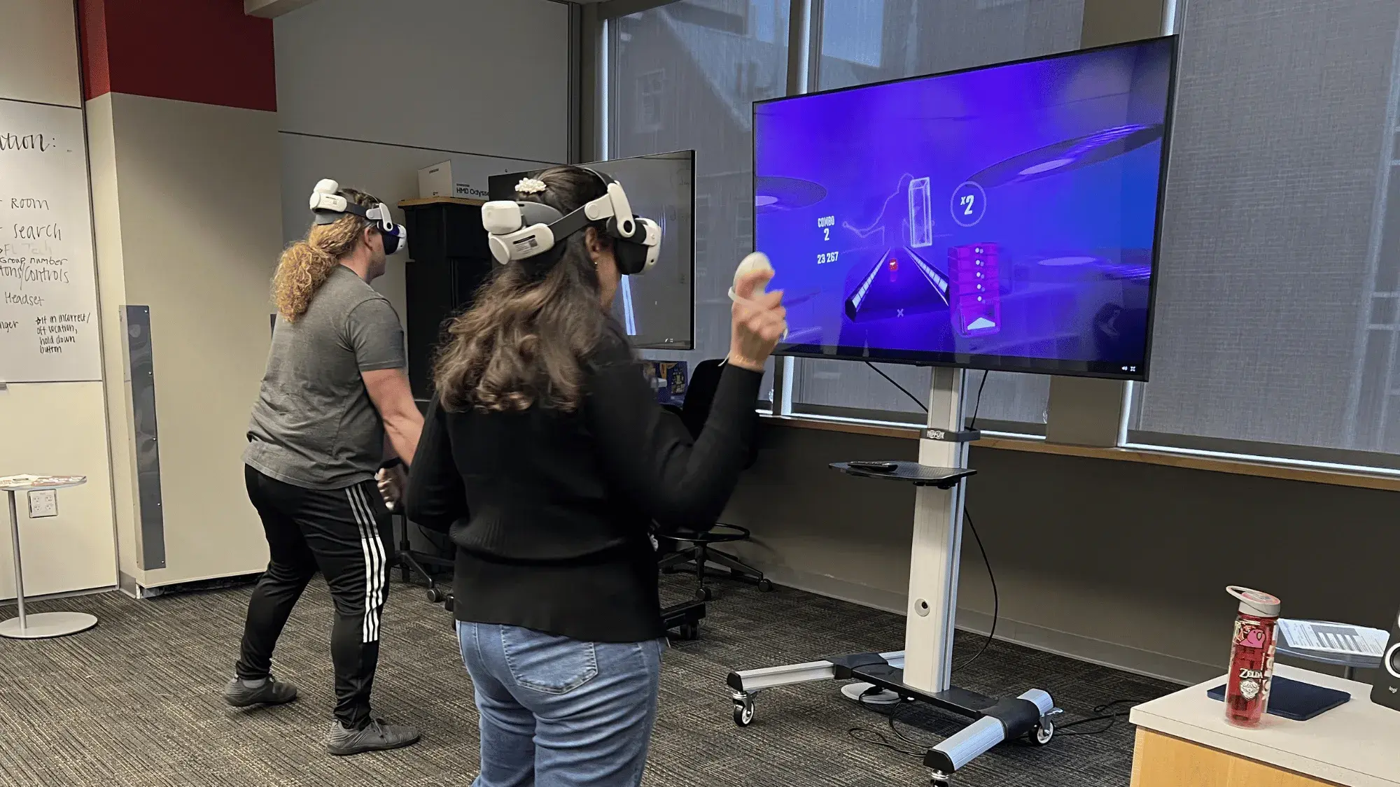 Two individuals play a VR game using VR headsets and hand controllers