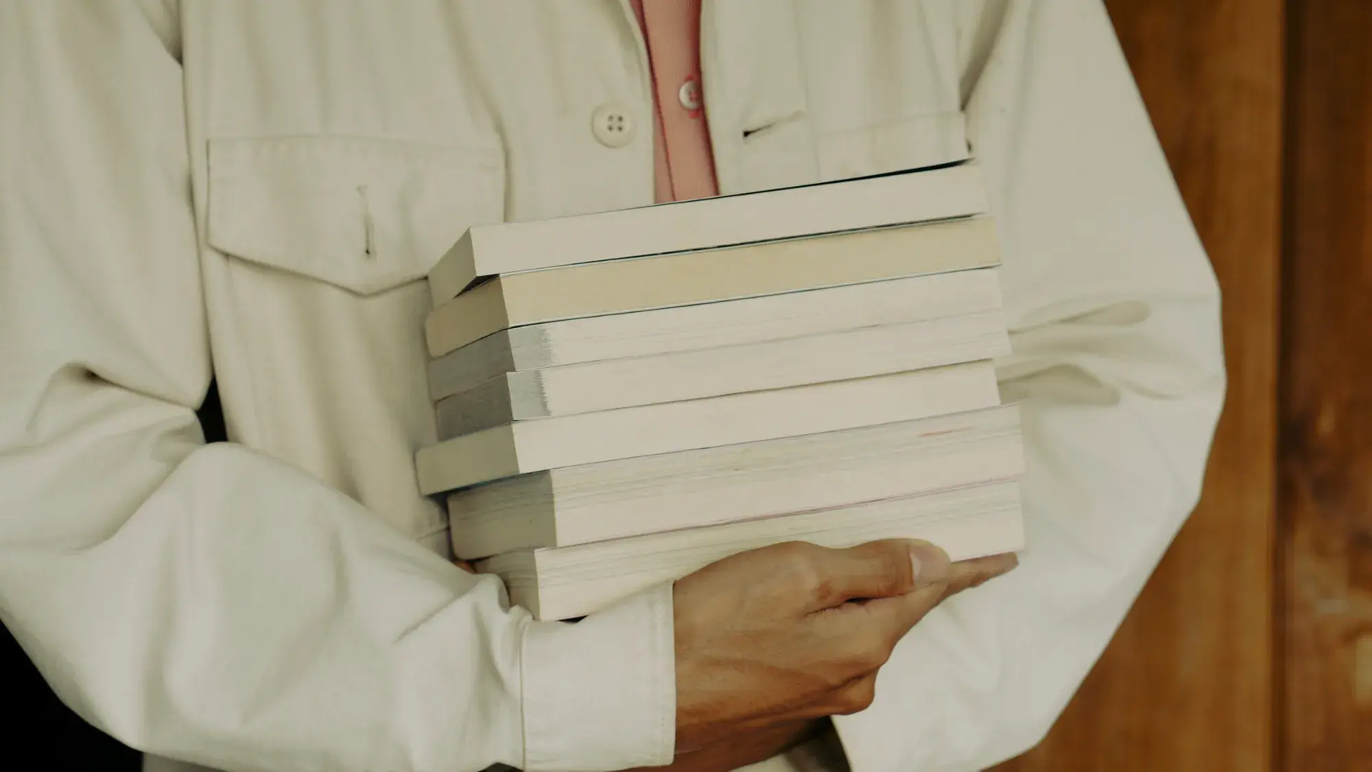 Person holding stack of books.