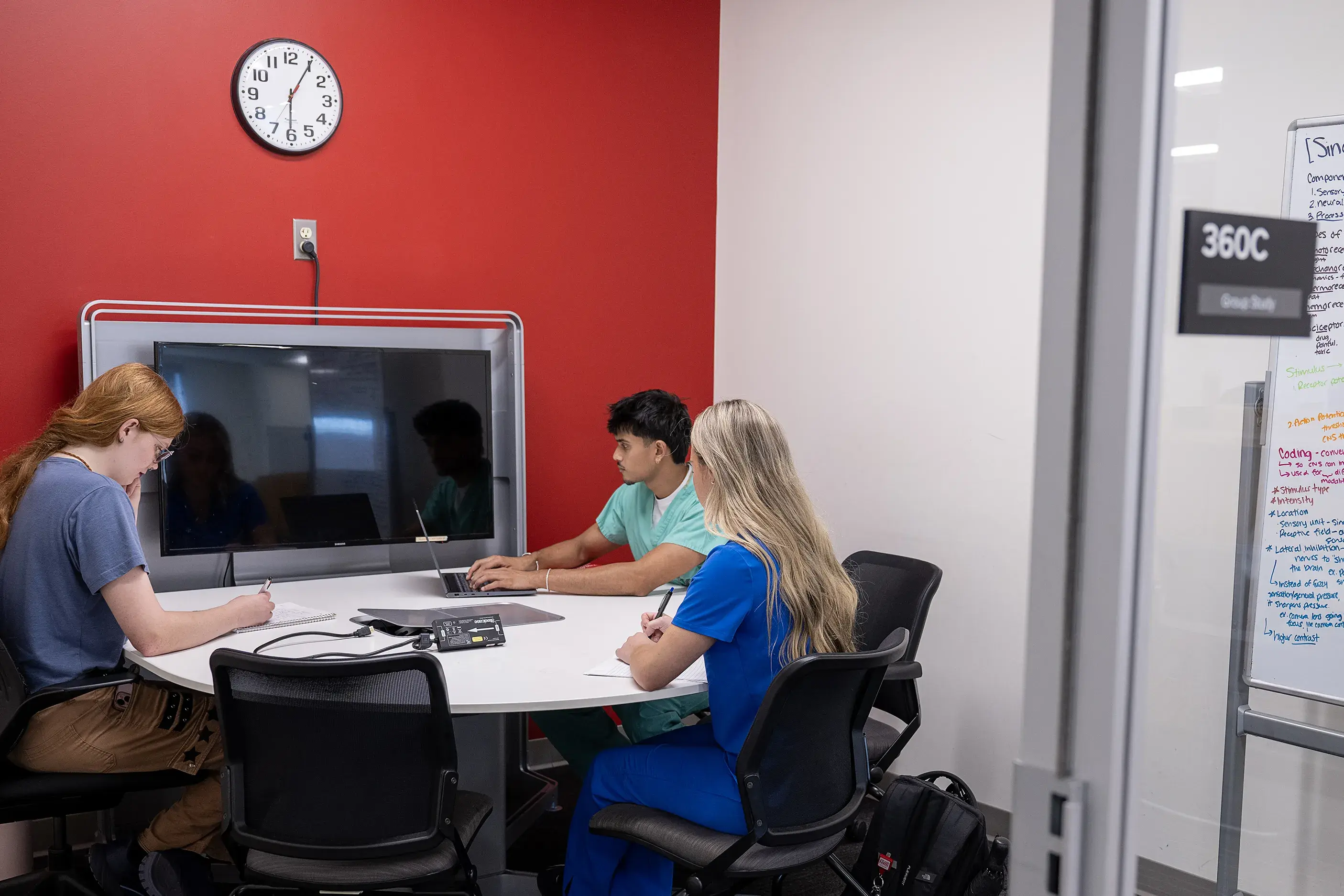 Three seated students studying in a study room
