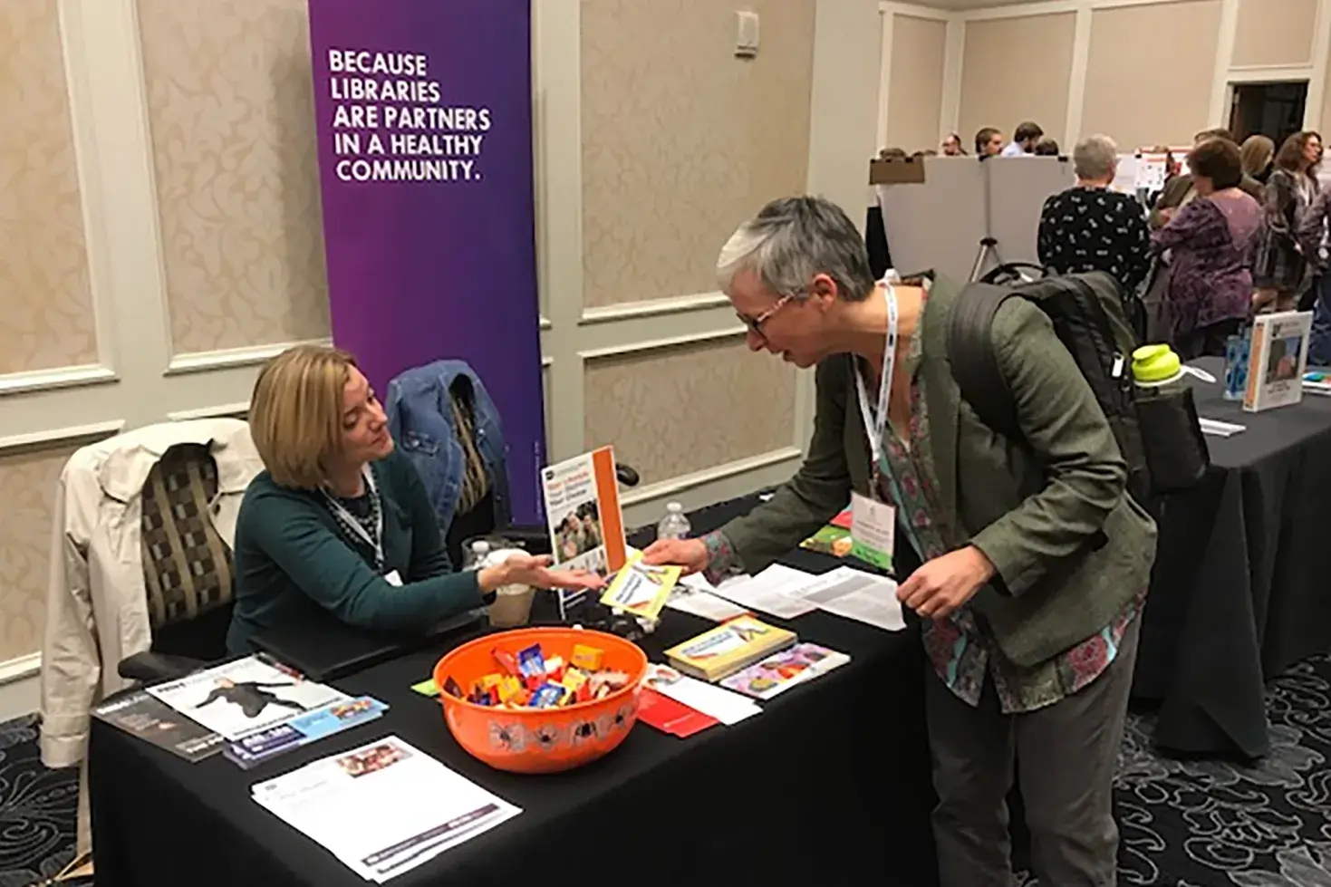 woman gathering pamphlets on health information at a booth during a an event 